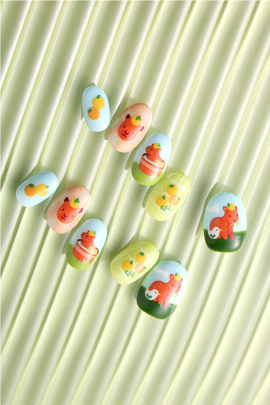 Press-on nails with cute capybara designs by Alice Lee. Features oranges and a capybara with a duckling.