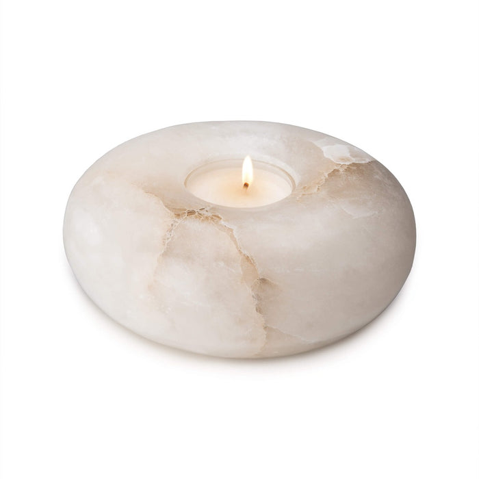 White alabaster tealight holder with lit candle and natural veining throughout.