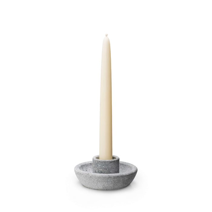 Gray soapstone candle holder with a cream taper candle inserted in the center socket.