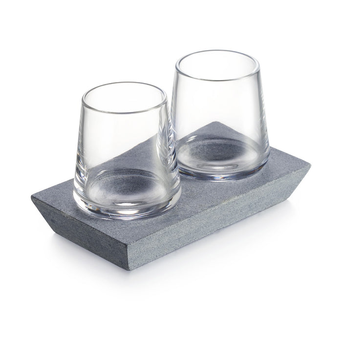 Two clear whiskey glasses with textured bases sit on a gray soapstone tray.