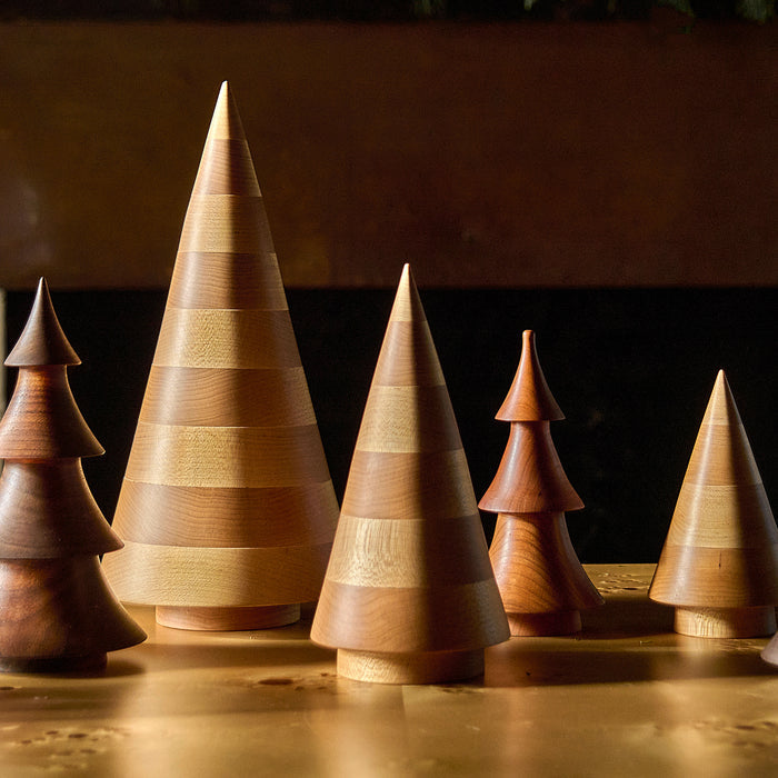 Five wooden cone-shaped evergreen trees in varying heights with horizontal bands, crafted from natural maple wood.