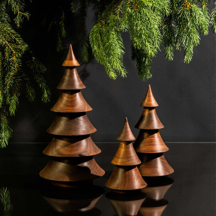 Three stacked walnut wood cone-shaped trees with varying heights and evergreen branches overhead.