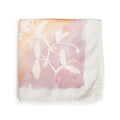 Apricot linen napkin with white botanical leaf print fading from peachy-orange to mauve tones.