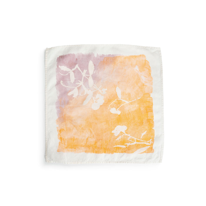 Cream linen napkin with apricot and mauve watercolor wash and white botanical leaf print.