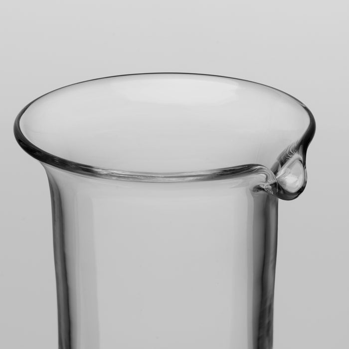 Clear glass pitcher with wide mouth rim and curved pouring spout on cylindrical body.