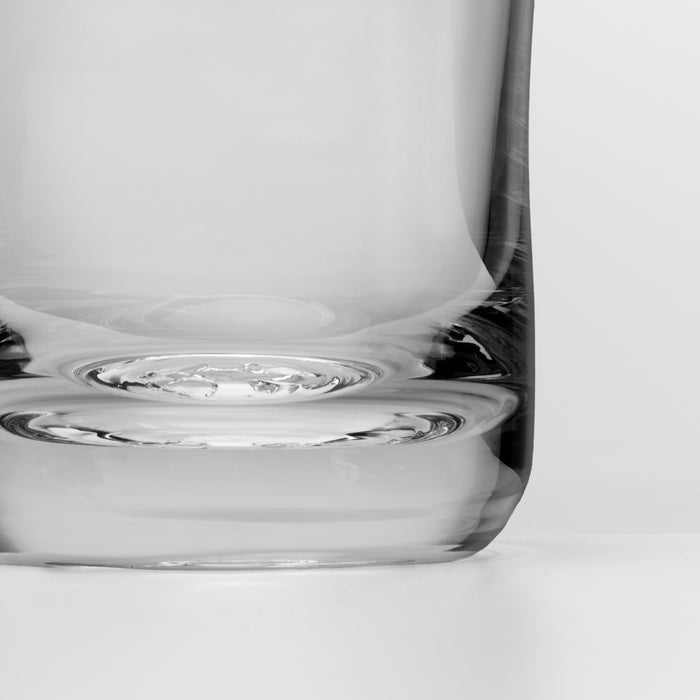 Clear glass bar pitcher with curved handle and spout, shown from side angle.
