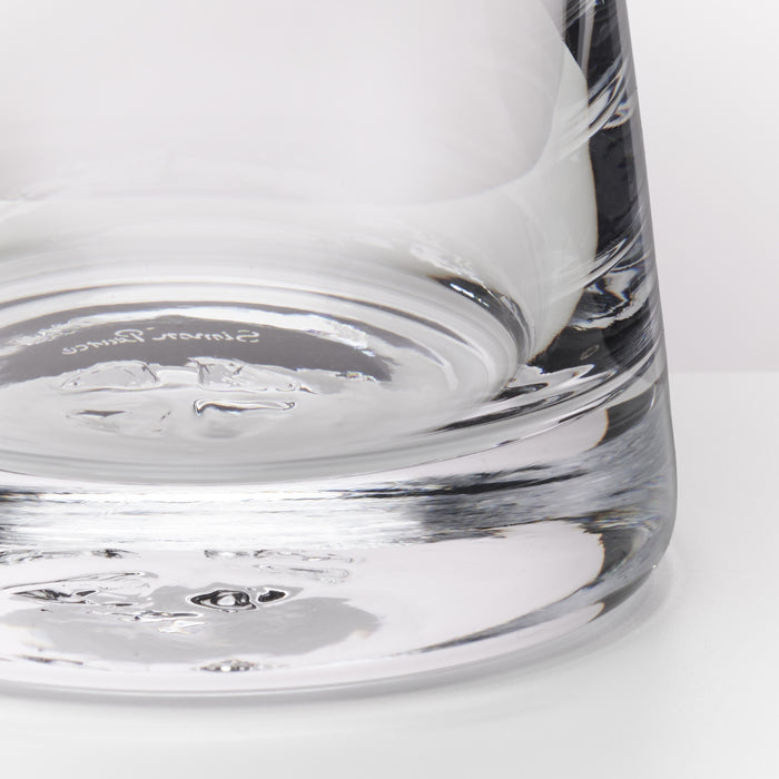 Close-up of a clear glass tumbler showing the thick textured base and a portion of the upper section on a white background.