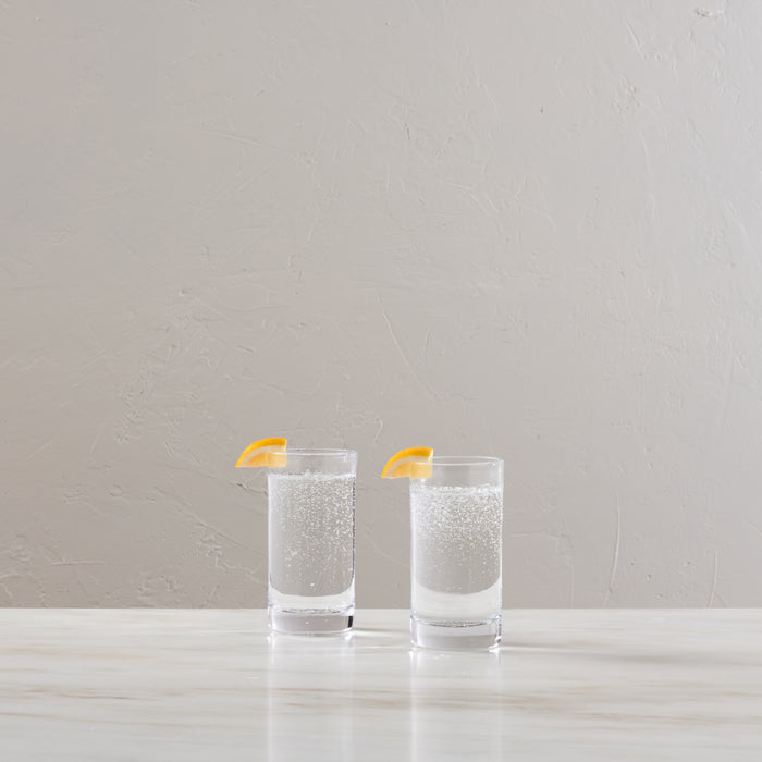 Two clear highball glasses filled with sparkling liquid and garnished with lemon twists.