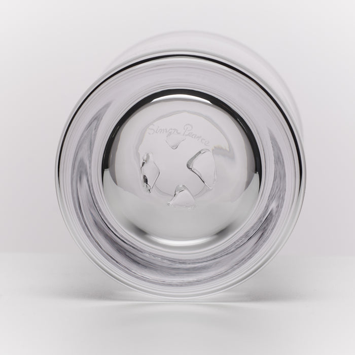 A clear glass tumbler shown from the bottom on a light gray background. The brand name 'Simon Pearce' is engraved on the bottom of the glass.