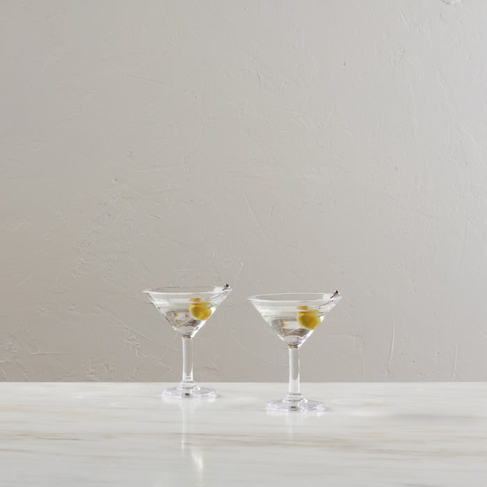 Two clear martini glasses with green olives on picks, filled with clear liquid.
