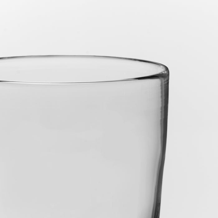 Empty clear glass with rounded rim against white background.