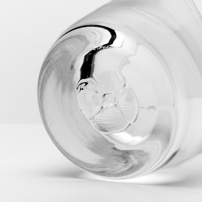 A close-up studio shot of a clear glass tumbler or cup base on a light gray background.