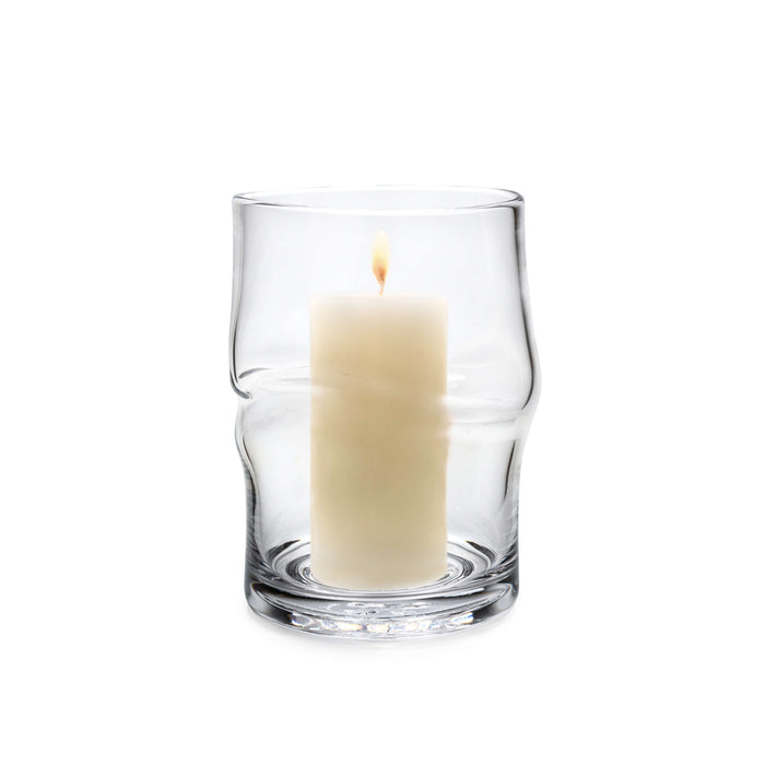 Clear glass hurricane with twisted sides holding a lit cream-colored pillar candle.