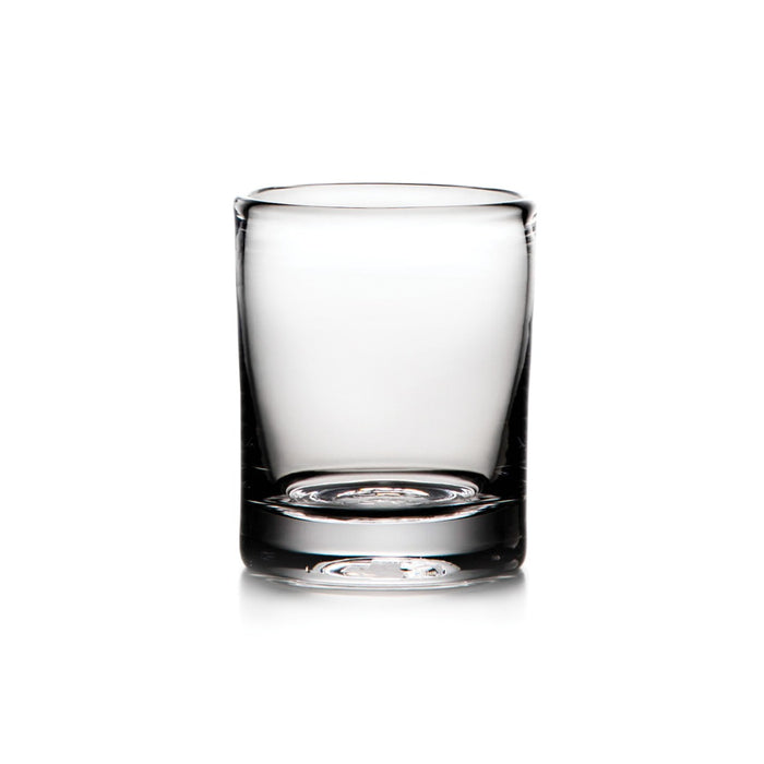Empty clear glass whiskey tumbler with thick base and weighted bottom on white background.