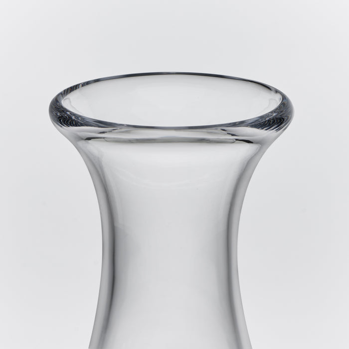 Clear glass decanter with curved tapered body and wide flared rim against white background.
