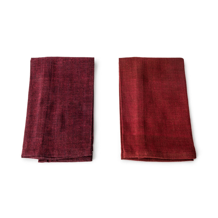 Two folded burgundy linen napkins displayed side by side showing textured weave fabric.