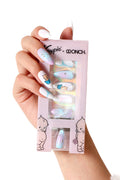 Aura Kewpie press-on nails with playful baby designs and iridescent pastel accents, held by a hand.