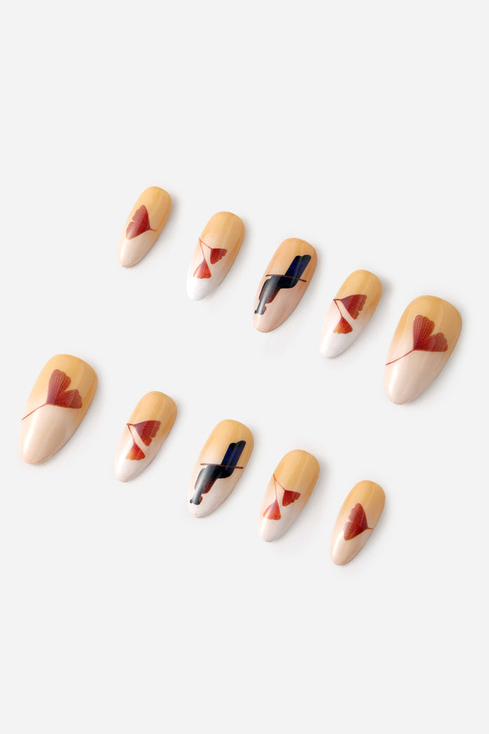 Autumn Ginkgo press-on nails with tan and white bases, featuring red ginkgo leaf designs and abstract black brushstrokes.
