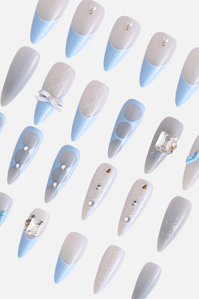 Baby blue and white press-on nails with bow accents and rhinestones.