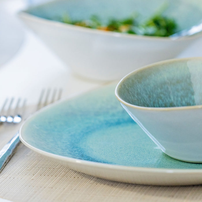 Ceramic dinnerware set with lagoon blue glaze interior, white exterior rim, stacked plate and bowl with fork.