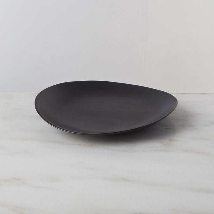 Slate-colored oval dinner plate with curved sides on a marble surface.