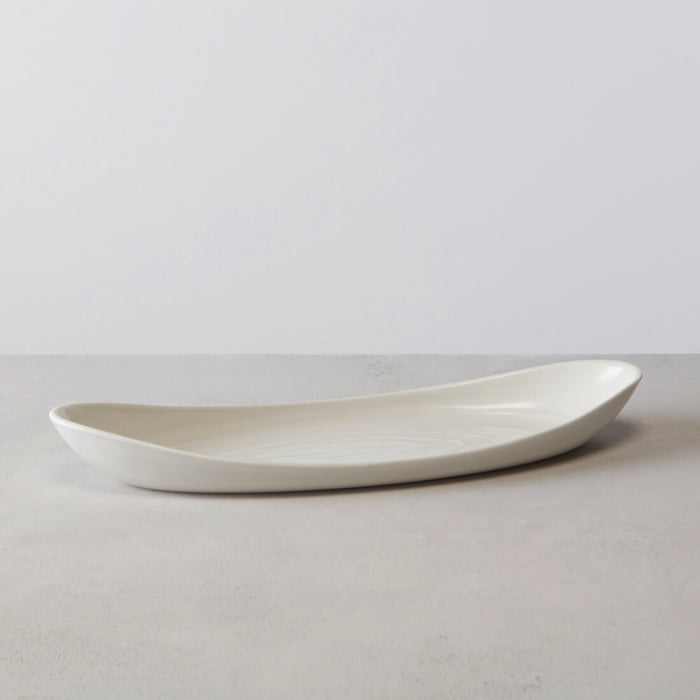 Large white ceramic serving platter with curved, elongated oval shape and shallow interior.