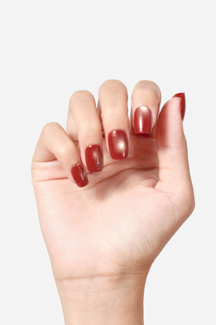 Hand showcasing glossy, square-shaped press-on nails in a rich, earthy wine-brown shade with subtle shimmer.
