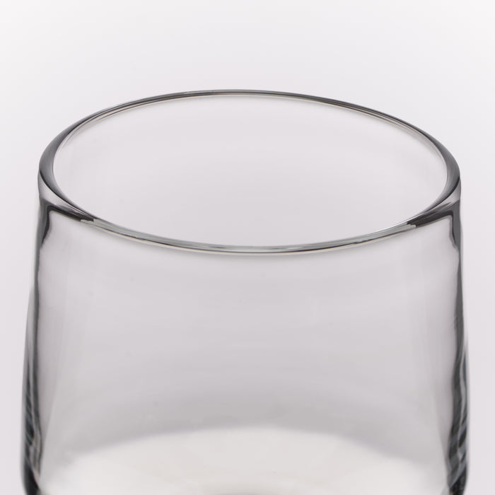 A close-up of a clear glass tumbler with a thick rim, shown against a plain white background.