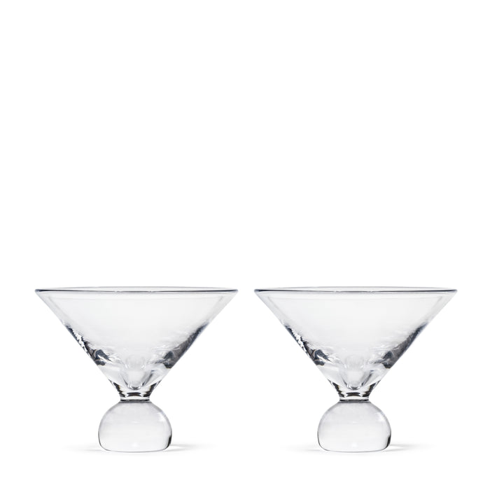 Two clear martini glasses with spherical bases side by side.