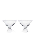 Two clear martini glasses with spherical bases side by side.