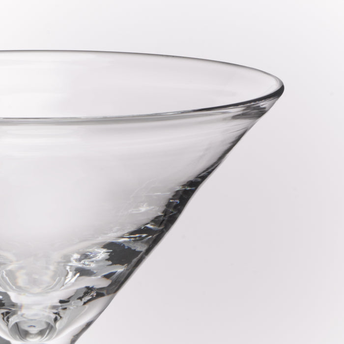 Close-up of a clear glass martini glass on a light gray background.
