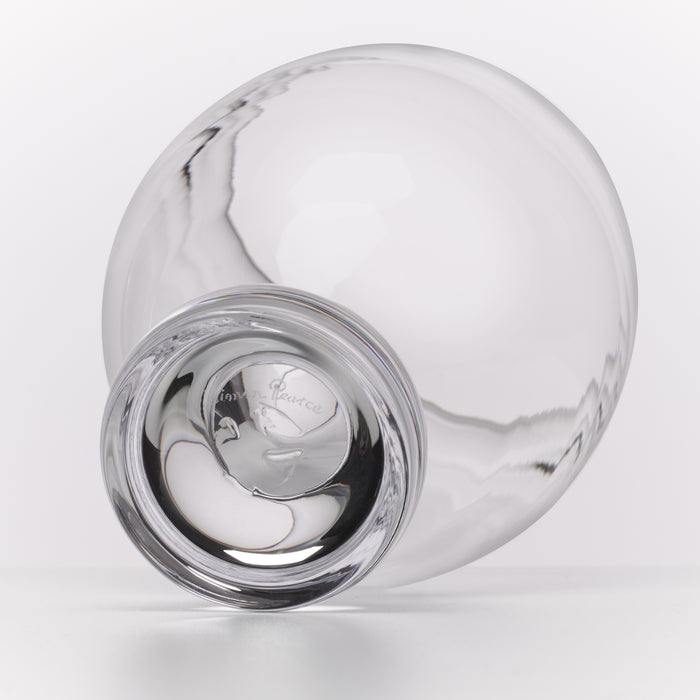 A clear glass carafe with a wide rounded body and a short, thick base, photographed on a clean white background. The outside of the base shows a printed logo.
