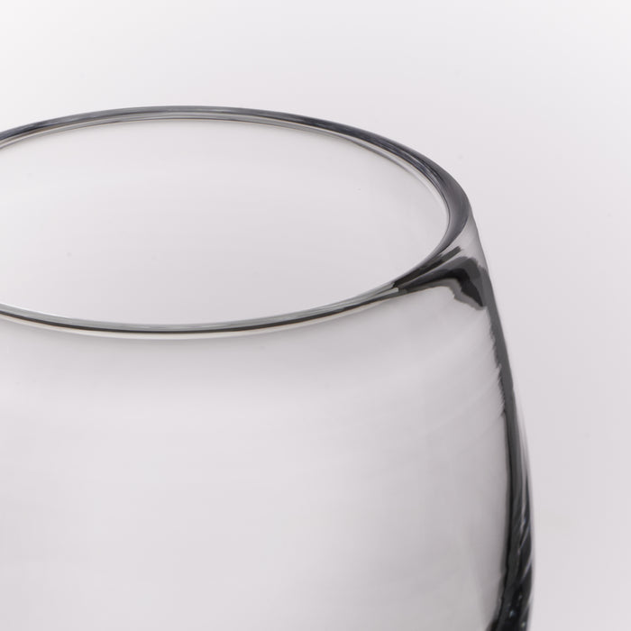 Close-up of a clear glass vessel, showing a smooth clear body against a light gray background.