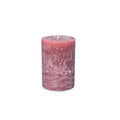 Pink pillar candle with white wick and textured surface.