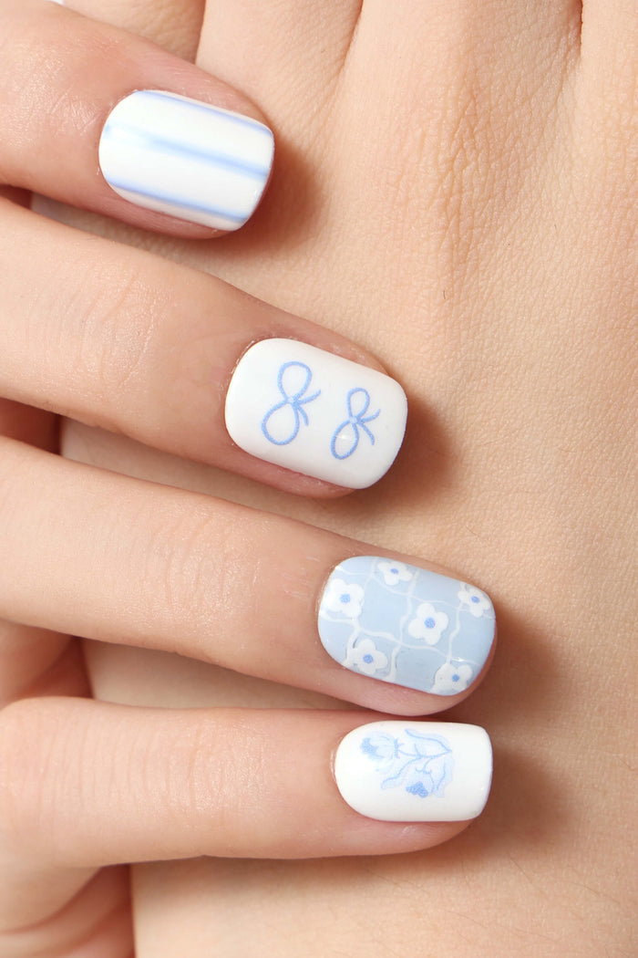 Blue Belle by Elaine Lee press-on nails featuring white base with blue floral patterns, bows, and stripes.