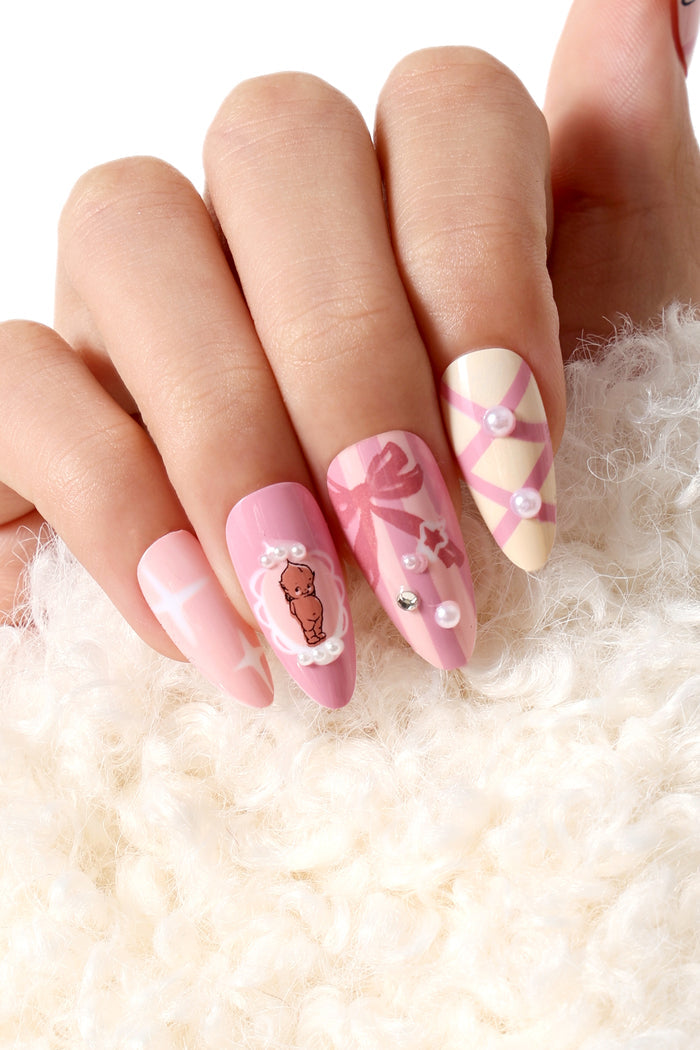 Pink press-on nails with Kewpie character, bows, and pearls. Almond shape.
