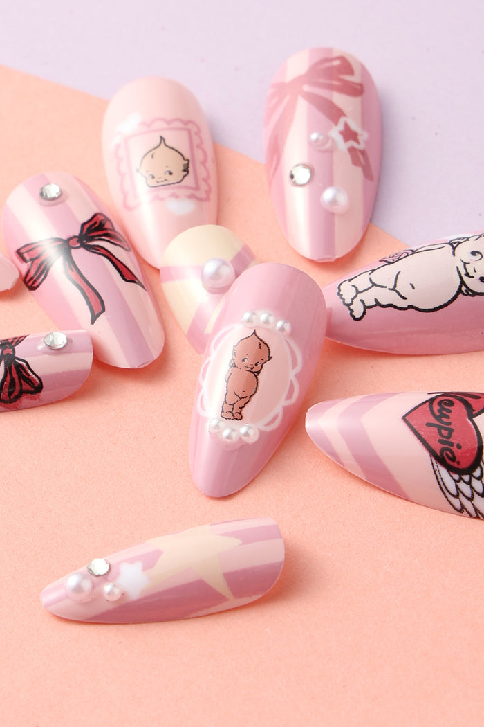 Pink press-on nails with Kewpie characters, bows, pearls, and stripes.
