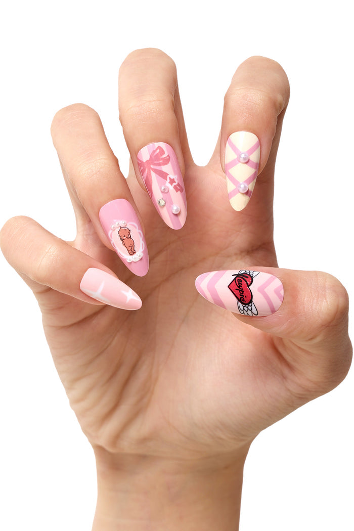 Pink press-on nails with Kewpie designs, bows, pearls, and a winged heart.