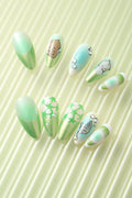 Bratty Kewpie press-on nails featuring cute baby designs, butterflies, and stars in green and blue ombre.