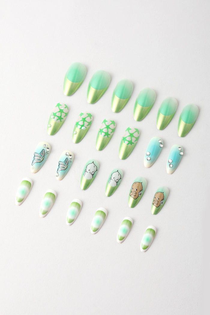 Press-on nails with green and gold gradient, star patterns, butterflies, and Kewpie baby designs.