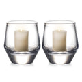 Two clear glass hurricane candle holders, each containing a cream-colored pillar candle with two wicks.