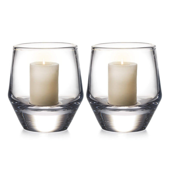 Two clear glass hurricane candle holders, each containing a cream-colored pillar candle with two wicks.