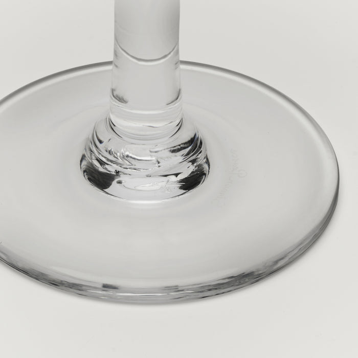 Close-up of a clear glass wine glass base and stem on a light gray background.
