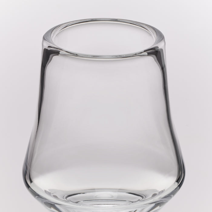 Clear glass tumbler with a wide rim and tapered base, photographed on a light gray studio background.