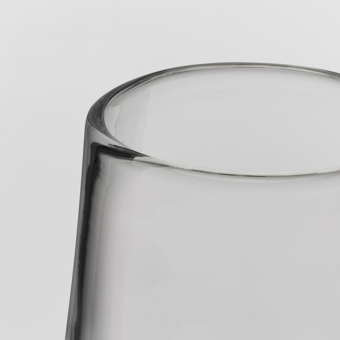 Close-up of a clear glass tumbler showing the rim and upper body against a light gray background.
