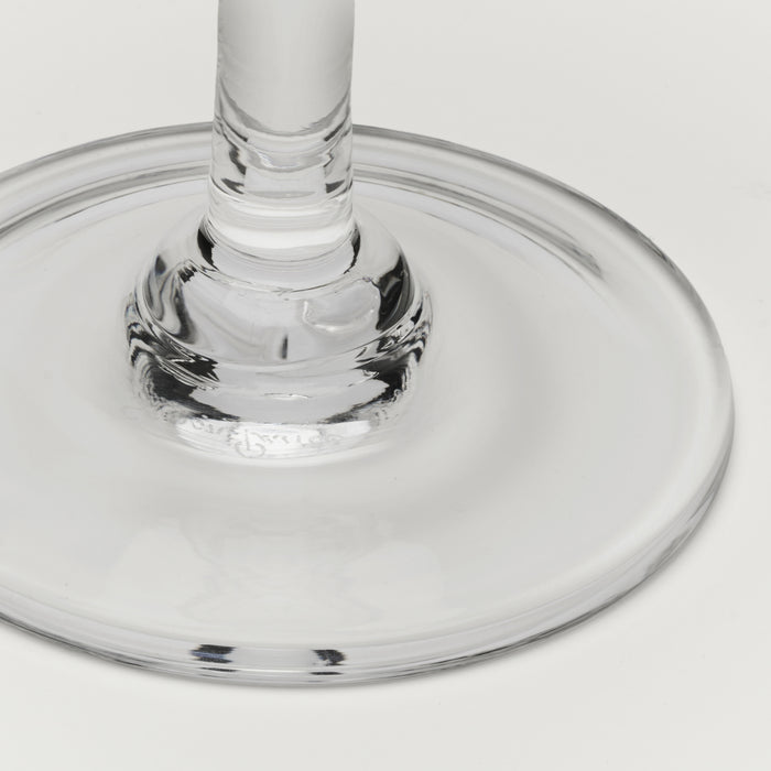 Close-up of a clear glass base and stem on a light gray background.