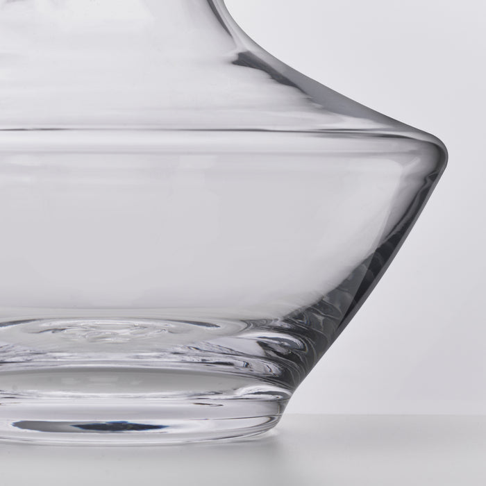 Clear glass decanter with curved pouring spout and wide bowl base, shown from side angle.