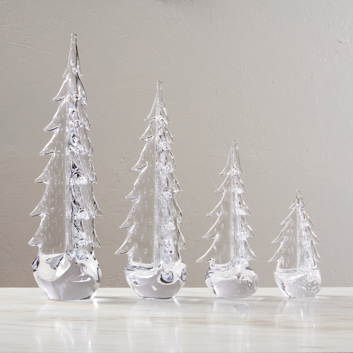 Four clear glass evergreen trees with pointed tops and white frosted bases, arranged in descending height order.