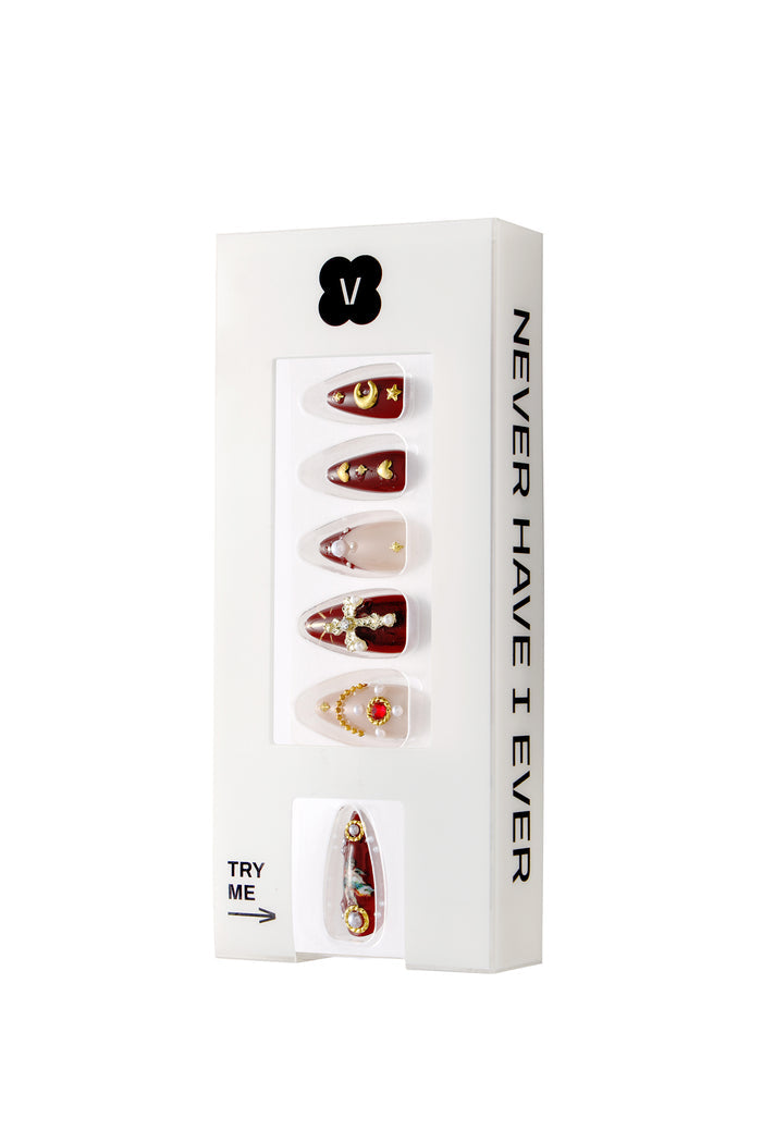 Burgundy French tip press-on nails with gold cherub and celestial designs, in 'Never Have I Ever' branded packaging.