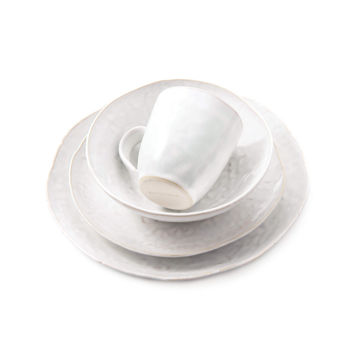 White dinnerware set with stacked plates, bowl, and mug featuring cloud-like surface texture.